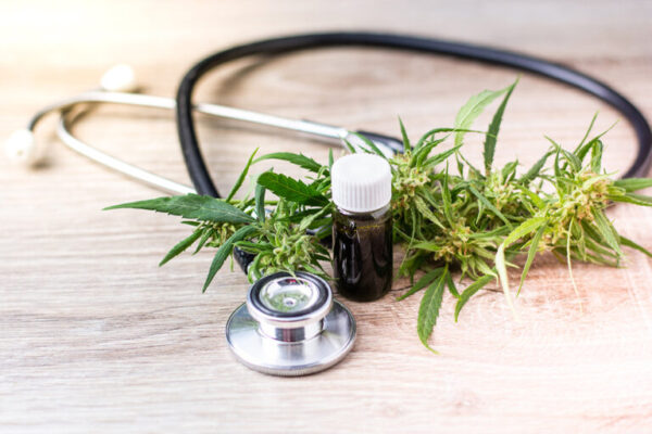 Cannabis oil in bottle, cannabis plant and stethoscope