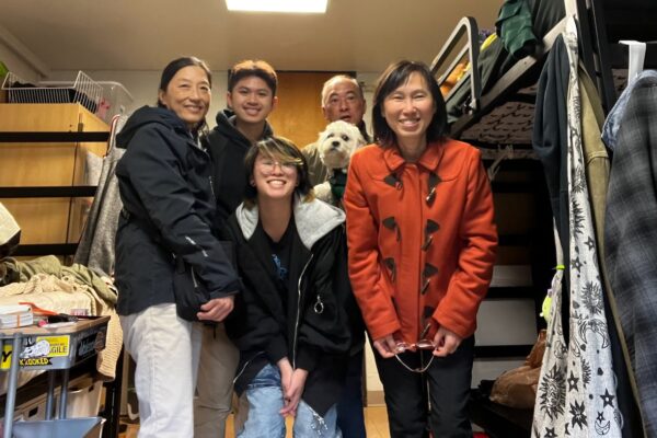 Wren Tsao posing with others while standing in a dorm room next to bunk beds.